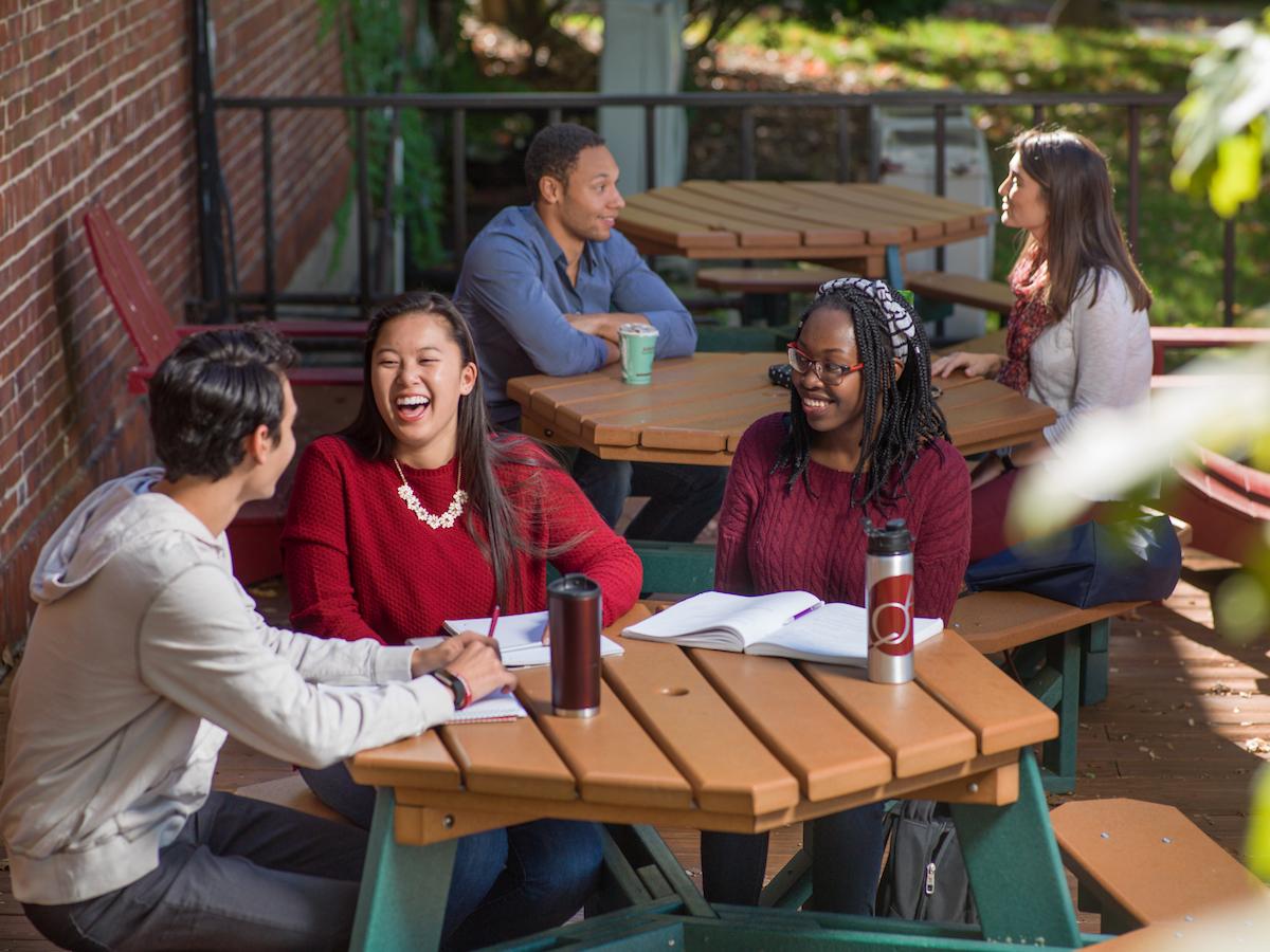 Students talking and smiling at a picnic table outside