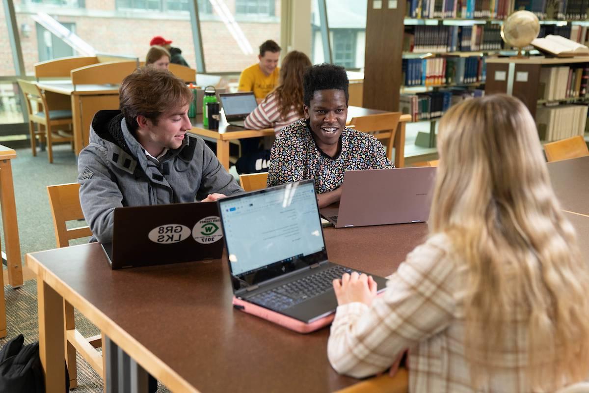 Students at a table with laptops talking