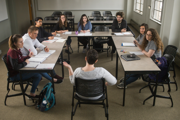 Students in small classroom gathered in a rectangle with desks