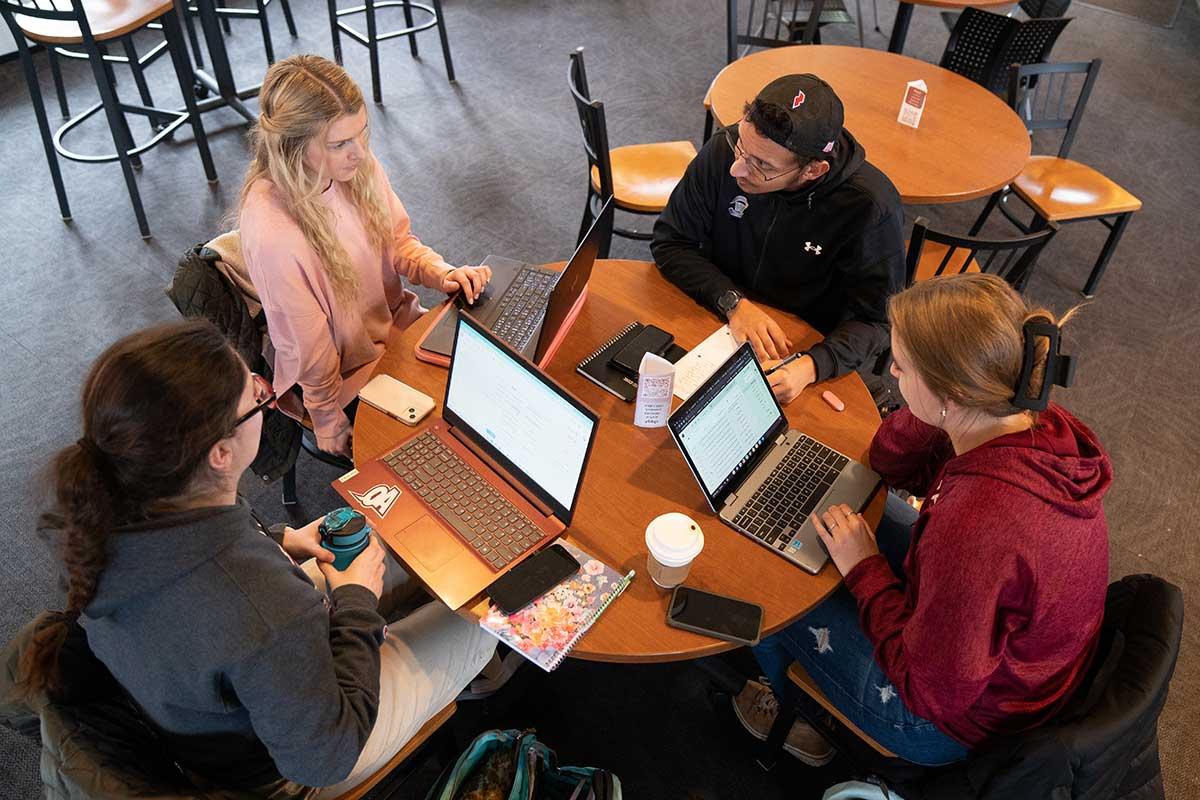 Four students working with laptops